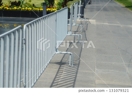 Light gray metal fences, barricades made of welded pipe with copy space on city street. Protruding legs for stability against overturning. Regulating movement of pedestrians, protesters, event guests Light gray metal fences, barricades made of welded pipe with copy space on city street. Protruding legs for stability against overturning. Regulating movement of pedestrians, protesters, event guests 131079321