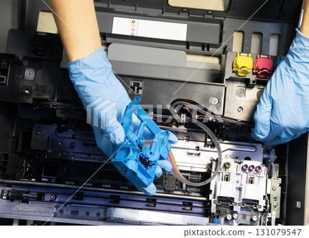 Top view of technician repairing and using printer repair tools. 131079547