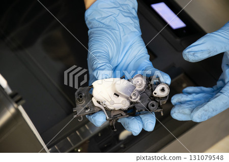 Top view of technician inspecting printer gear assembly. Top view of technician inspecting printer gear assembly. 131079548