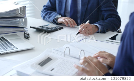 Business team analyzing financial documents, using calculators and laptop, working together on project in modern office. Audit and taxes in business Business team analyzing financial documents, using calculators and laptop, working together on project in modern office. Audit and taxes in business 131079833
