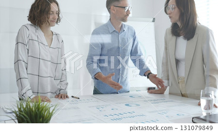 Professional colleagues reviewing financial reports, collaborating on strategic planning in contemporary workspace with collaborative atmosphere 131079849
