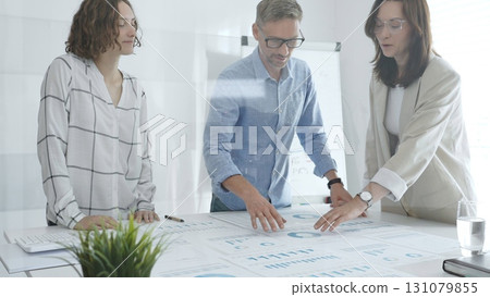 Professional colleagues reviewing financial reports, collaborating on strategic planning in contemporary workspace with collaborative atmosphere Professional colleagues reviewing financial reports, collaborating on strategic planning in contemporary workspace with collaborative atmosphere 131079855