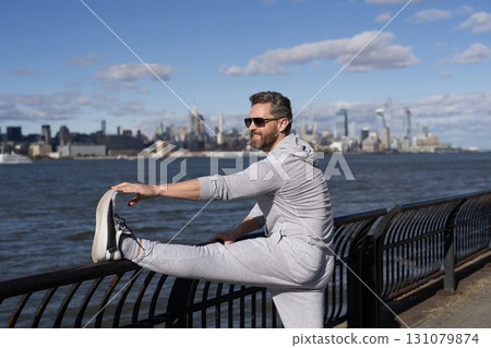 Stretching routine of sportsman in NY. Sportsman stretching his muscles after running. Sportsman stretch to improve flexibility. Sport man stretching and warm up for workout. Dynamic flexibility Stretching routine of sportsman in NY. Sportsman stretching his muscles after running. Sportsman stretch to improve flexibility. Sport man stretching and warm up for workout. Dynamic flexibility 131079874