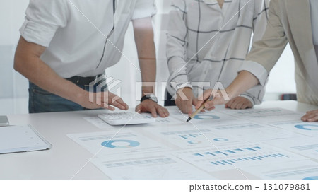 Professional team reviewing financial charts and graphs, working together in modern office space, developing strategic improvements. Business people concept 131079881