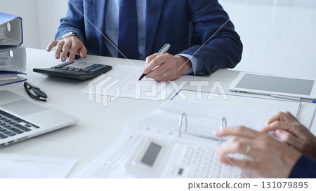 Close up of female accountant hands using calculator while collaborating with male colleague in office, calculating taxes and analyzing financial data. Audit and taxes in business Close up of female accountant hands using calculator while collaborating with male colleague in office, calculating taxes and analyzing financial data. Audit and taxes in business 131079895