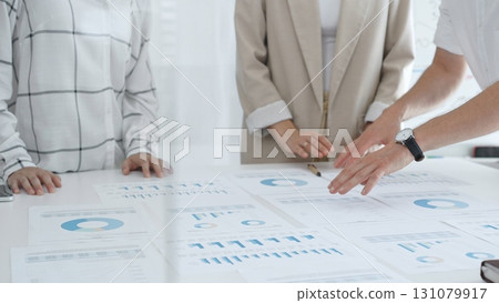 Business team analyzing financial charts and graphs, pointing at statistics and discussing data, working together on business project in modern office. Business people concept 131079917