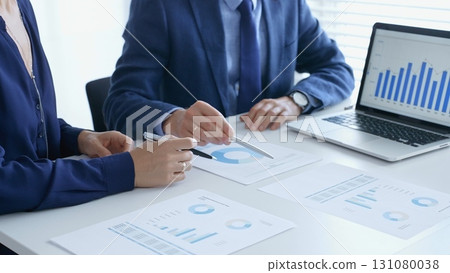 Business professionals reviewing financial data, pointing at laptop charts and shared documents during collaborative strategy session. Business people and finance concept 131080038
