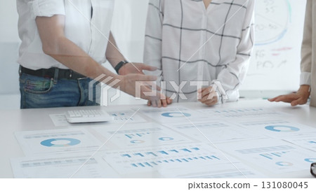 Group of business people is collaborating in modern office environment, analyzing financial data and charts, evaluating performance and developing company growth strategy 131080045