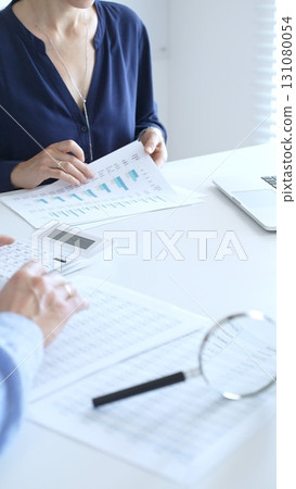 Two professional accountants analyzing financial reports with magnifying glass and calculator, performing accounting and auditing tasks in the office, close up of hands. Audit and taxes in business Two professional accountants analyzing financial reports with magnifying glass and calculator, performing accounting and auditing tasks in the office, close up of hands. Audit and taxes in business 131080054