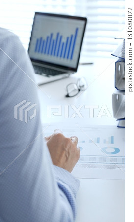 Business partners reviewing financial documents charts and diagrams , working collaboratively at white desk in office. Audit and taxes in business Business partners reviewing financial documents charts and diagrams , working collaboratively at white desk in office. Audit and taxes in business 131080072