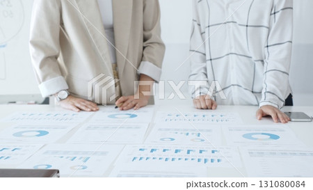 Professional women analyzing financial charts, discussing business strategy in modern light office, in collaborative corporate environment. Business people concept 131080084