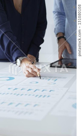 Professional team reviewing financial documents, pointing at charts on desk, collaborating to analyze data and strategize business growth. Business people concept 131080108