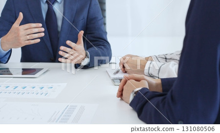 Business professionals discussing financial charts on tablet, collaborating closely while reviewing project data in modern corporate workspace 131080506