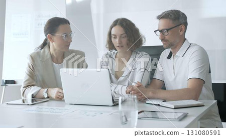 Professional team reviewing project data on laptop, working together in modern office environment, collaborating with focused corporate energy. Business people concept Professional team reviewing project data on laptop, working together in modern office environment, collaborating with focused corporate energy. Business people concept 131080591
