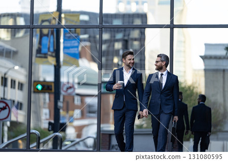 Businessmen go to work. Business talking. Two businessmen in elegant business suit. Walking colleague. Colleague and friends. Two successful business men walking outdoor. Business district Businessmen go to work. Business talking. Two businessmen in elegant business suit. Walking colleague. Colleague and friends. Two successful business men walking outdoor. Business district 131080595