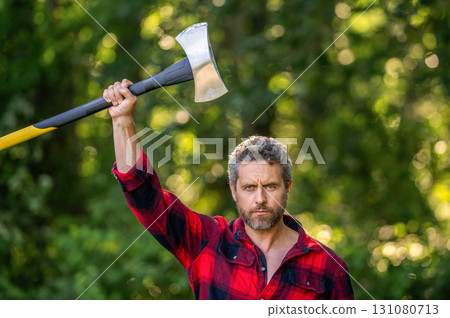 Strong man work in forest. Lumberjack men in forest with axe. Lumberjack carries axe. Handsome man with axe. Lumberjack in woods with an ax. Lumberjack in checkered shirt with heavy axe 131080713