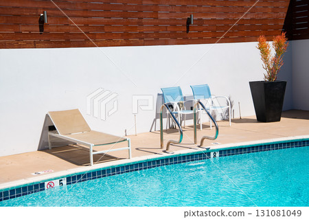 Poolside with sunlounger and chairs for recreation at outdoor backyard pool in summer 131081049