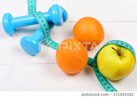 sport concept, dumbbells weight with measuring tape, orange and apple 131081082