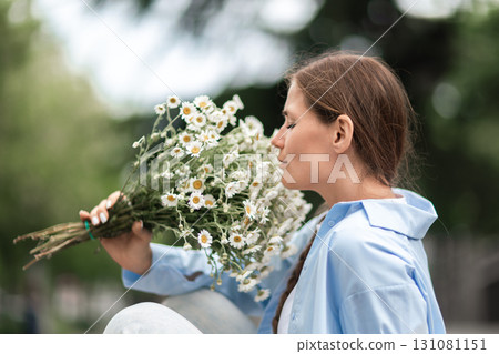 Daisies Woman Bouquet: Girl enjoys fragrant flowers outdoors during daytime. 131081151