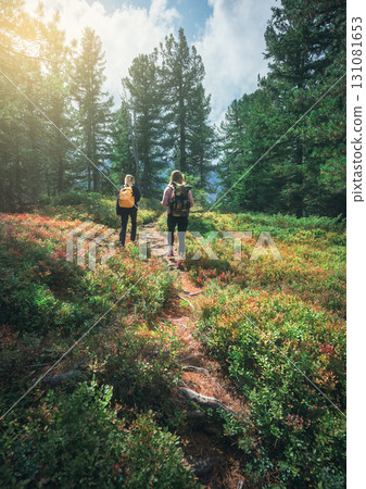 Two young women with backpacks hiking on a forest path 131081653