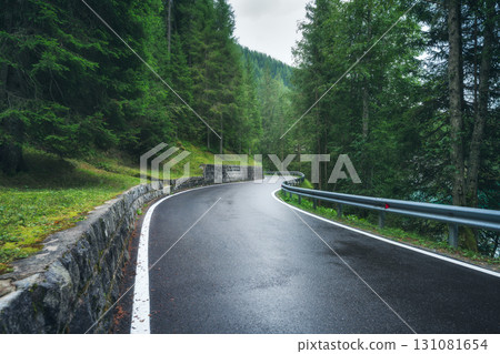 Wet mountain road curving through dense green forest Wet mountain road curving through dense green forest 131081654