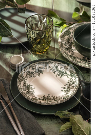 Beautiful table setting with different green rustik plates on wooden background in bright morning light Beautiful table setting with different green rustik plates on wooden background in bright morning light 131082363