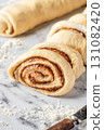 Cutted roll of dough on white marble background. Making cinnamon rolls process. Cinnabon preparation 131082420