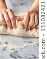 Women's hands kneading dough on white marble table. Making cinnamon rolls process. Cinnabon preparation 131082421