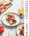 Caprese sandwich or toast with mozzarrella balls, cherry tomatoes, olive oil, pepper and fresh basil leaves. Healthy vegetarian breakfast, snack or lunch. White marble background 131082422