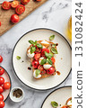 Caprese sandwich or toast with mozzarrella balls, cherry tomatoes, olive oil and fresh basil leaves top view close up on white marble background 131082424