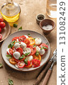 Caprese salad with sliced tomatoes, mozzarella, basil, olive oil on brown textured background close up 131082429