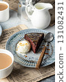 A piece of chocolate brownie cake on blue plate served with a scoop of ice cream and caramel topping with coffee 131082431