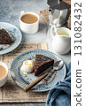 A piece of chocolate brownie cake on blue plate served with a scoop of ice cream and caramel topping with coffee 131082432