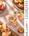 Summer cold drinks: homemade iced peach lemonade with mint in glass on pink tile background in bright morning light, top view 131082433