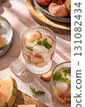 Summer cold drinks: homemade iced peach lemonade with mint in glass on pink tile background in bright morning light 131082434