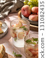 Summer cold drinks: homemade iced peach lemonade with mint in glass on pink tile background in bright morning light 131082435