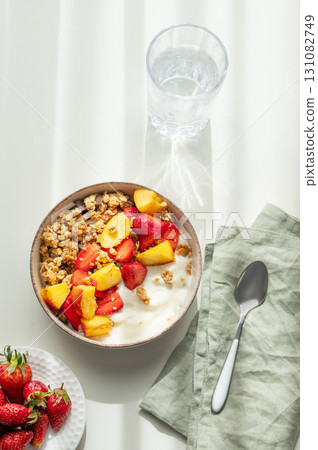 Granola or muesli with natural greek yogurt, strawberry and peach in a bowl on a white background Granola or muesli with natural greek yogurt, strawberry and peach in a bowl on a white background 131082749