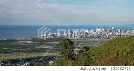Panoramic view of ocean, coastal cityscape and green countryside from hilltop under clear blue sky Panoramic view of ocean, coastal cityscape and green countryside from hilltop under clear blue sky 131082751