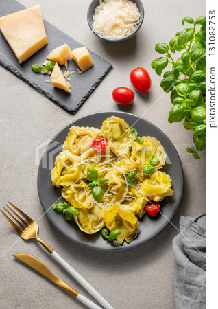 Tortellini pasta with parmesan, pesto and basil in a plate on a light background with cheese Tortellini pasta with parmesan, pesto and basil in a plate on a light background with cheese 131082758