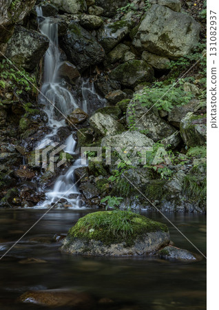 A small waterfall cascading over mossy rocks 131082937