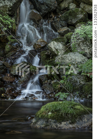 A small waterfall cascading over mossy rocks 131082938