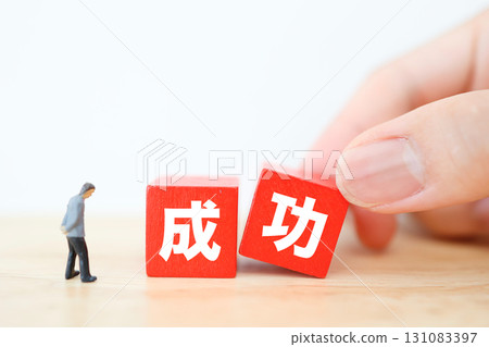 Miniature businessman and red block looking at success Miniature businessman and red block looking at success 131083397