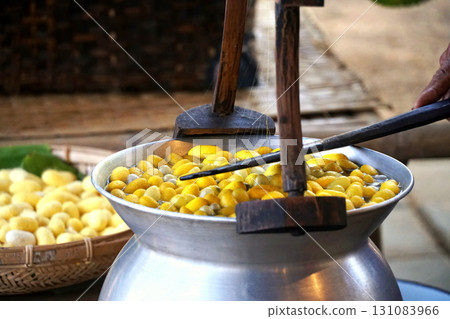 Boiling silkworm cocoons in a pot to separate them into fibers to produce silk thread. Boiling silkworm cocoons in a pot to separate them into fibers to produce silk thread. 131083966
