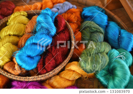 Tie of colorful and shiny beautiful silk yarn dyed placed in a pile of round bamboo baskets. Prepared for use as a raw material for weaving silk. Tie of colorful and shiny beautiful silk yarn dyed placed in a pile of round bamboo baskets. Prepared for use as a raw material for weaving silk. 131083970