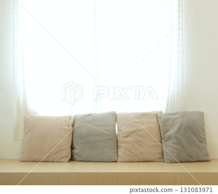 A wooden bench with a translucent curtain. Bright with natural light from the rear window. Decorated with fluffy pillows 131083971