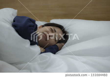 一名婦女在床上的看一個智能手機 一名婦女在床上的看一個智能手機 131084460