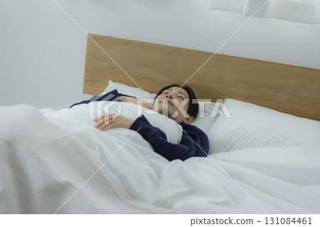 一名婦女在床上的看一個智能手機 一名婦女在床上的看一個智能手機 131084461
