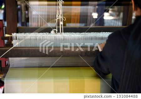 Women's hands weaving silk on a traditional wooden loom. Women's hands weaving silk on a traditional wooden loom. 131084488