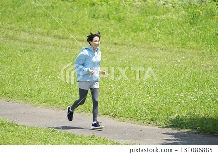 一位 40 多歲的女性在戶外跑步，全身 131086885