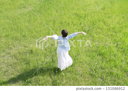 Woman taking a deep breath in the field, overhead view, back view 131086912